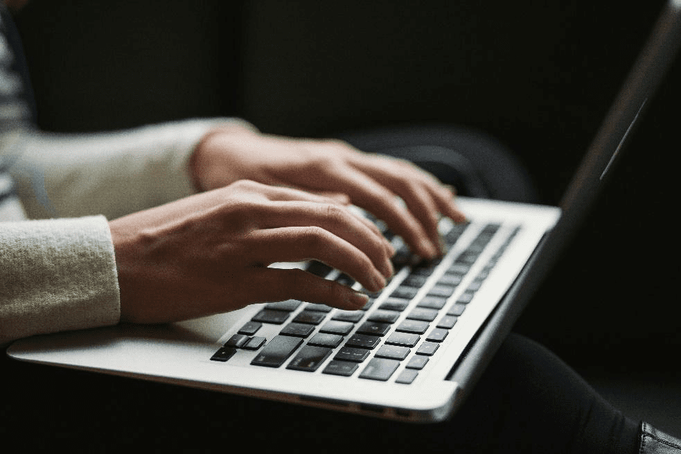 close-up of person typing on laptop to access region-restricted content