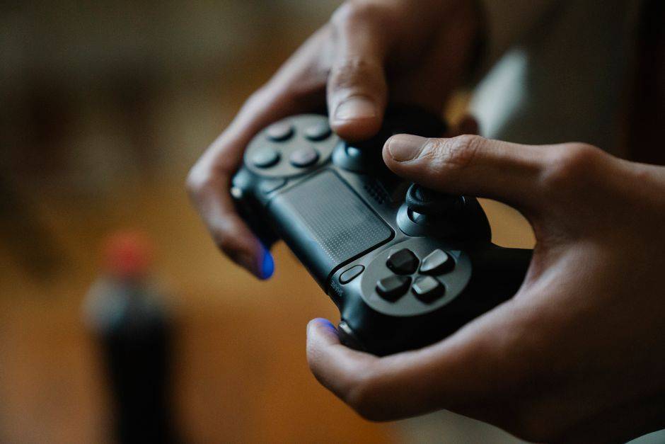 Hands holding a gaming controller illustrating gaming setups and cybersecurity.