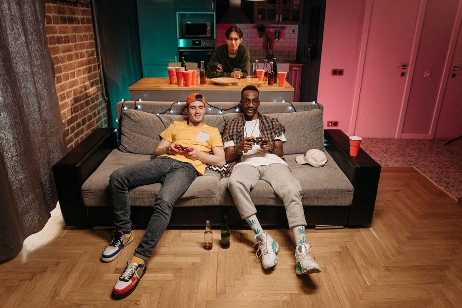 Friends gaming on consoles in a living room, illustrating VPN use for secure console gaming.