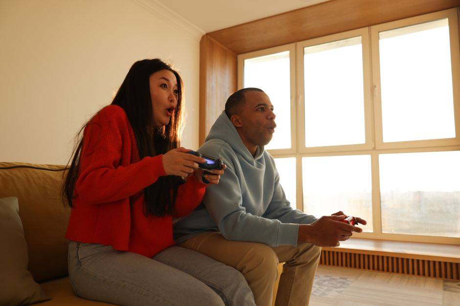 Couple playing video games on couch illustrating gaming setups and cybersecurity.