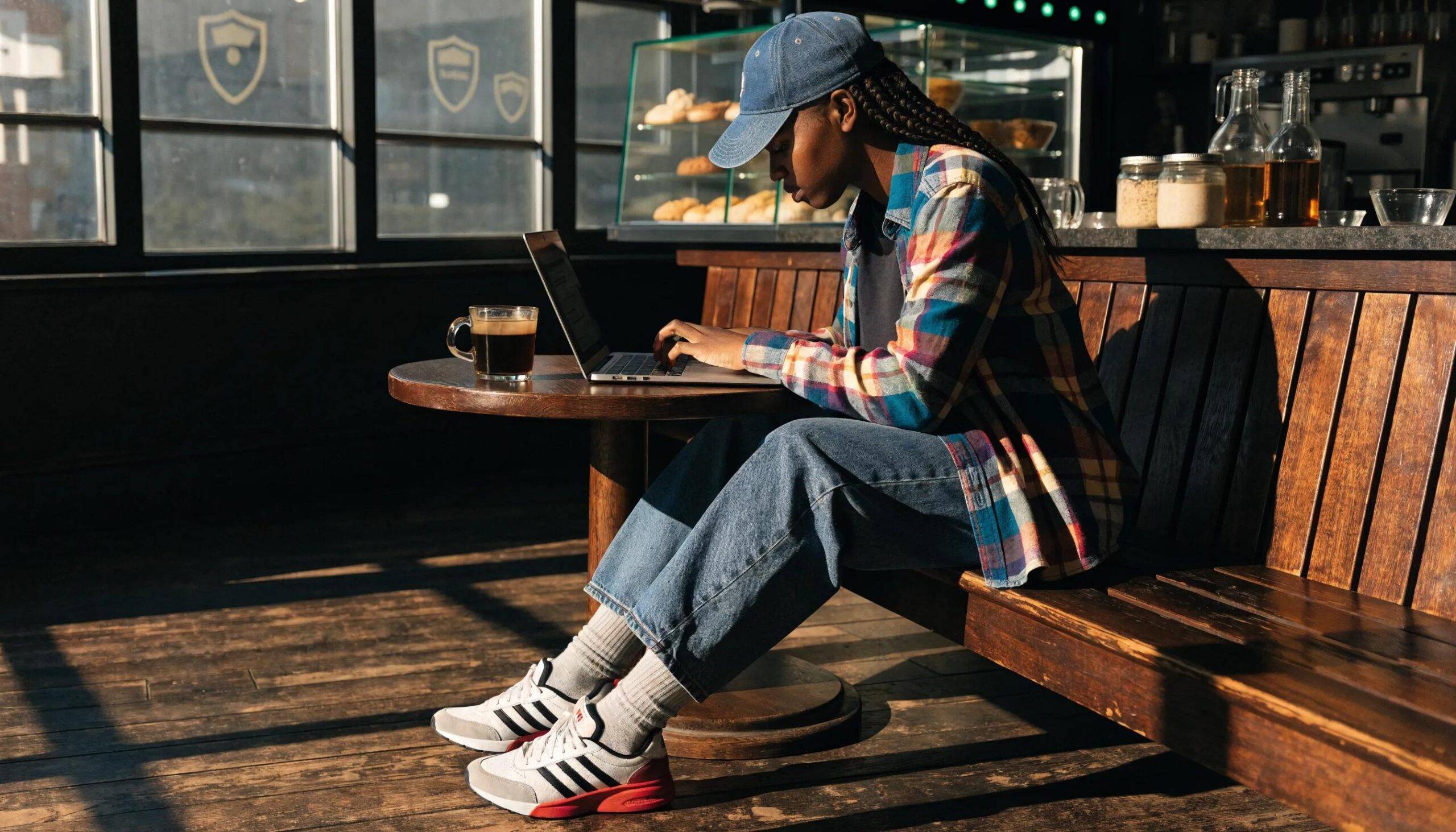 Person using a laptop in a coffee shop, representing online privacy and security concepts
