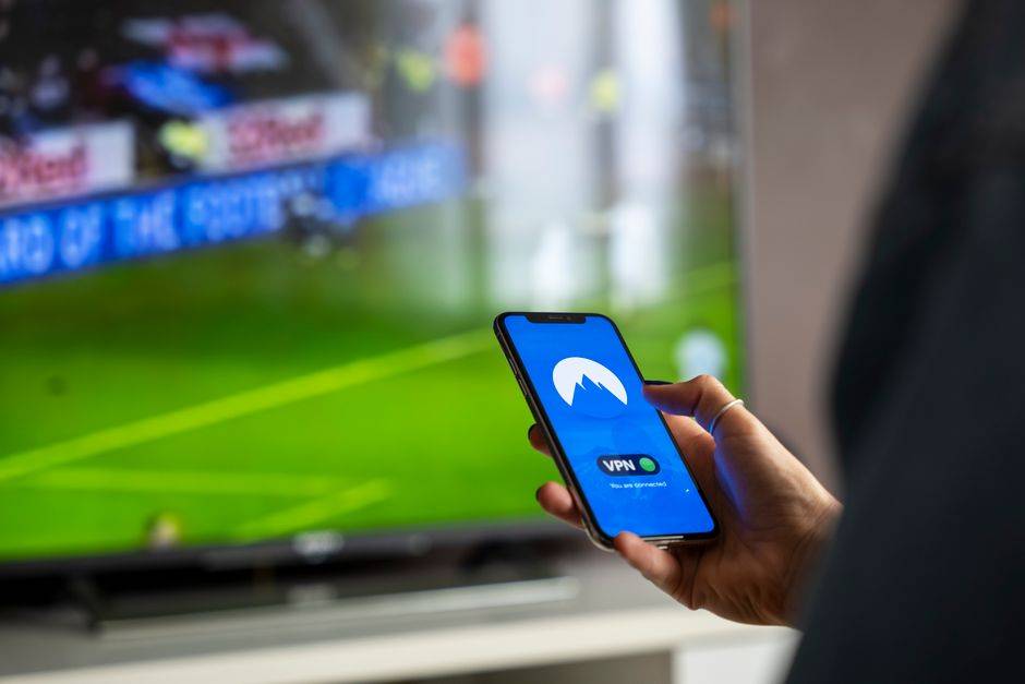 Smartphone displaying VPN app with a large screen showing a soccer game in the background.